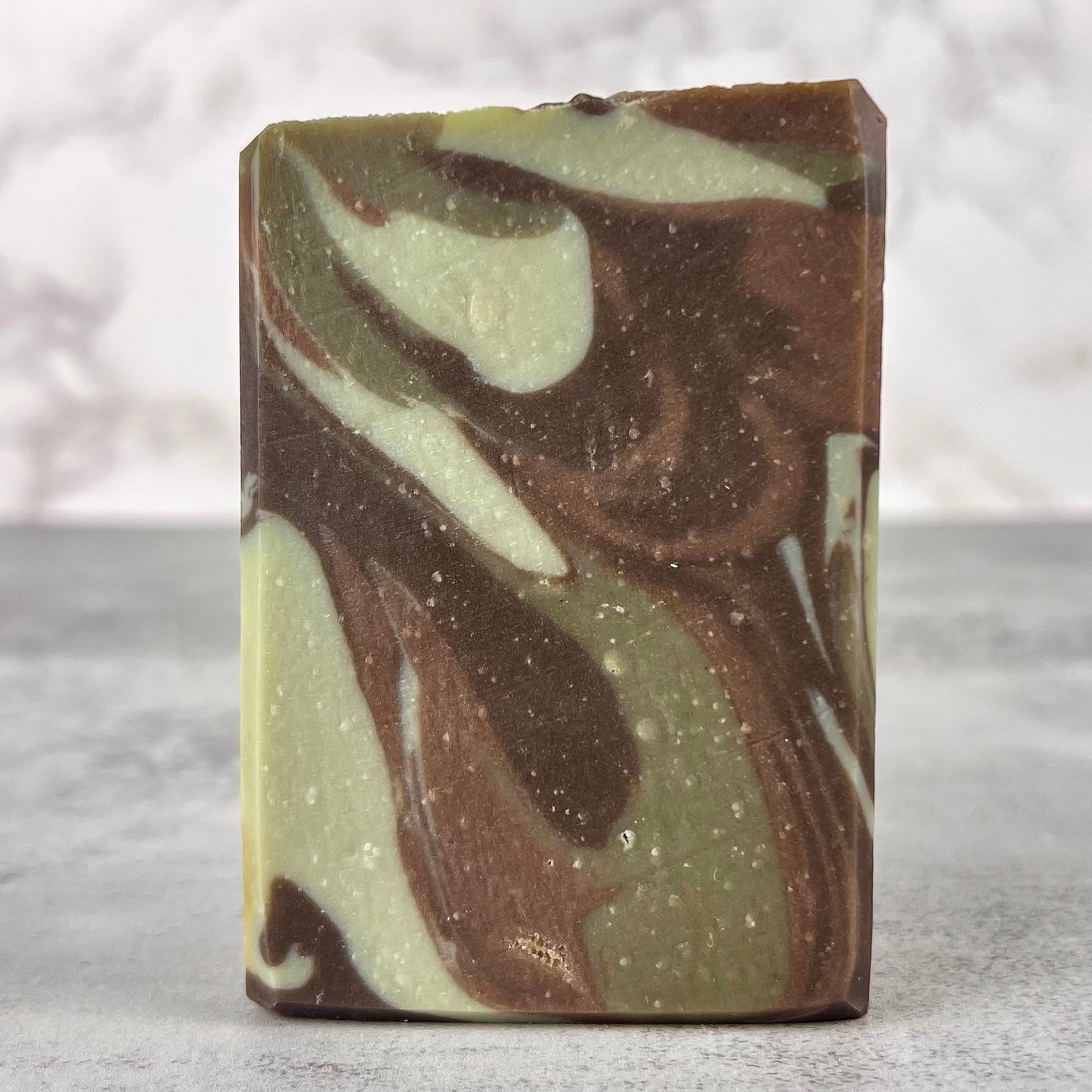 Marbled brown and green soap bar on a neutral background