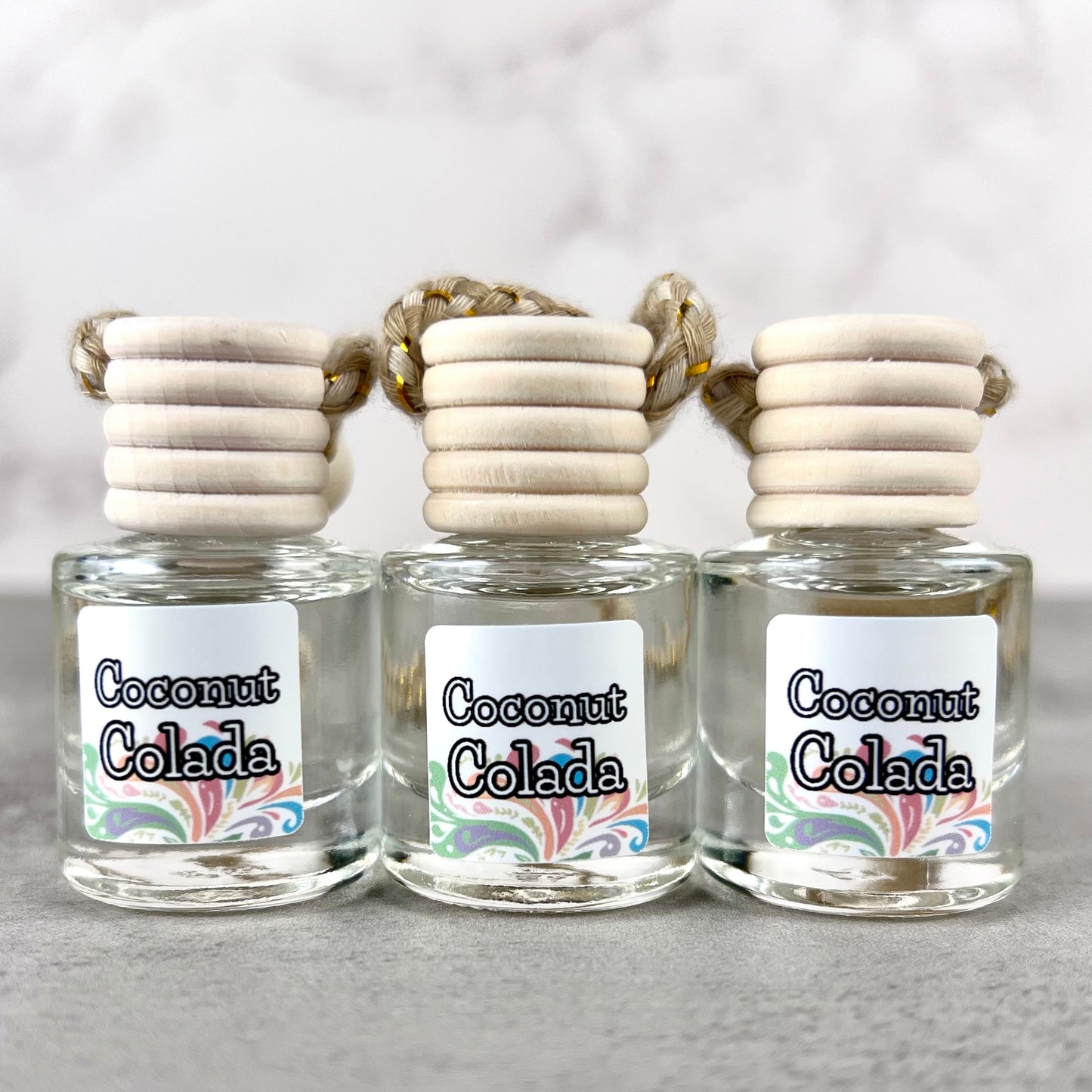 Three car diffusers with 'Coconut Colada' labels on a gray background
