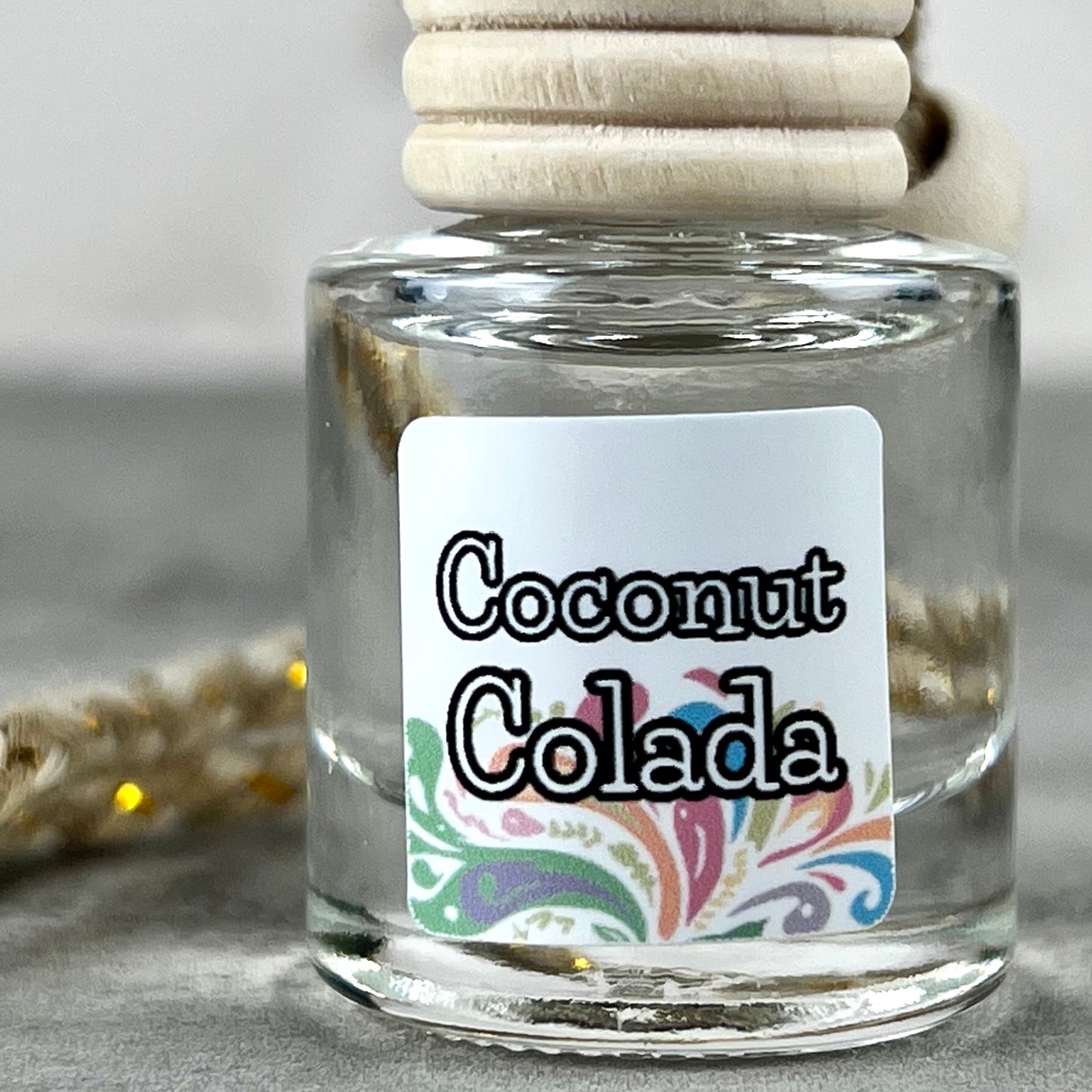 Car diffuser with "Coconut Colada" label on neutral background.