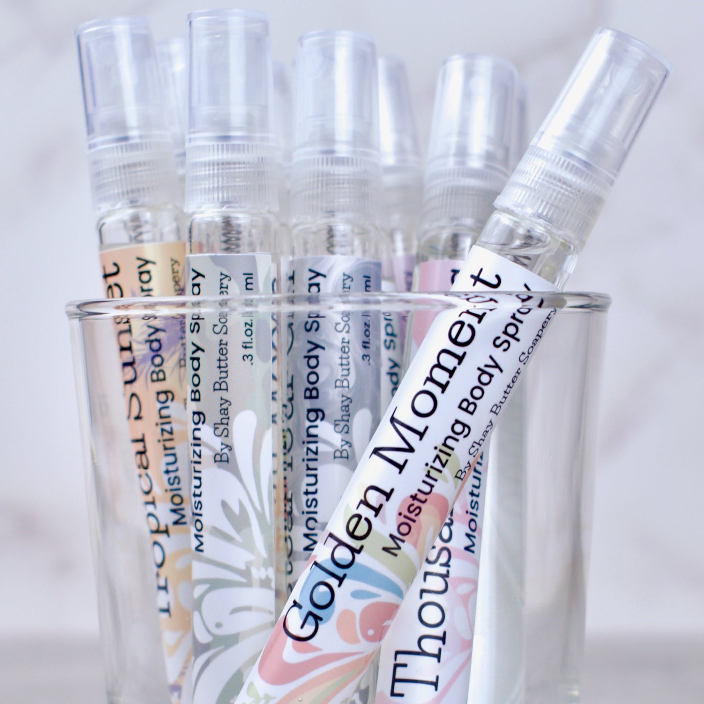 Set of small spray bottles with visible labels on a light background