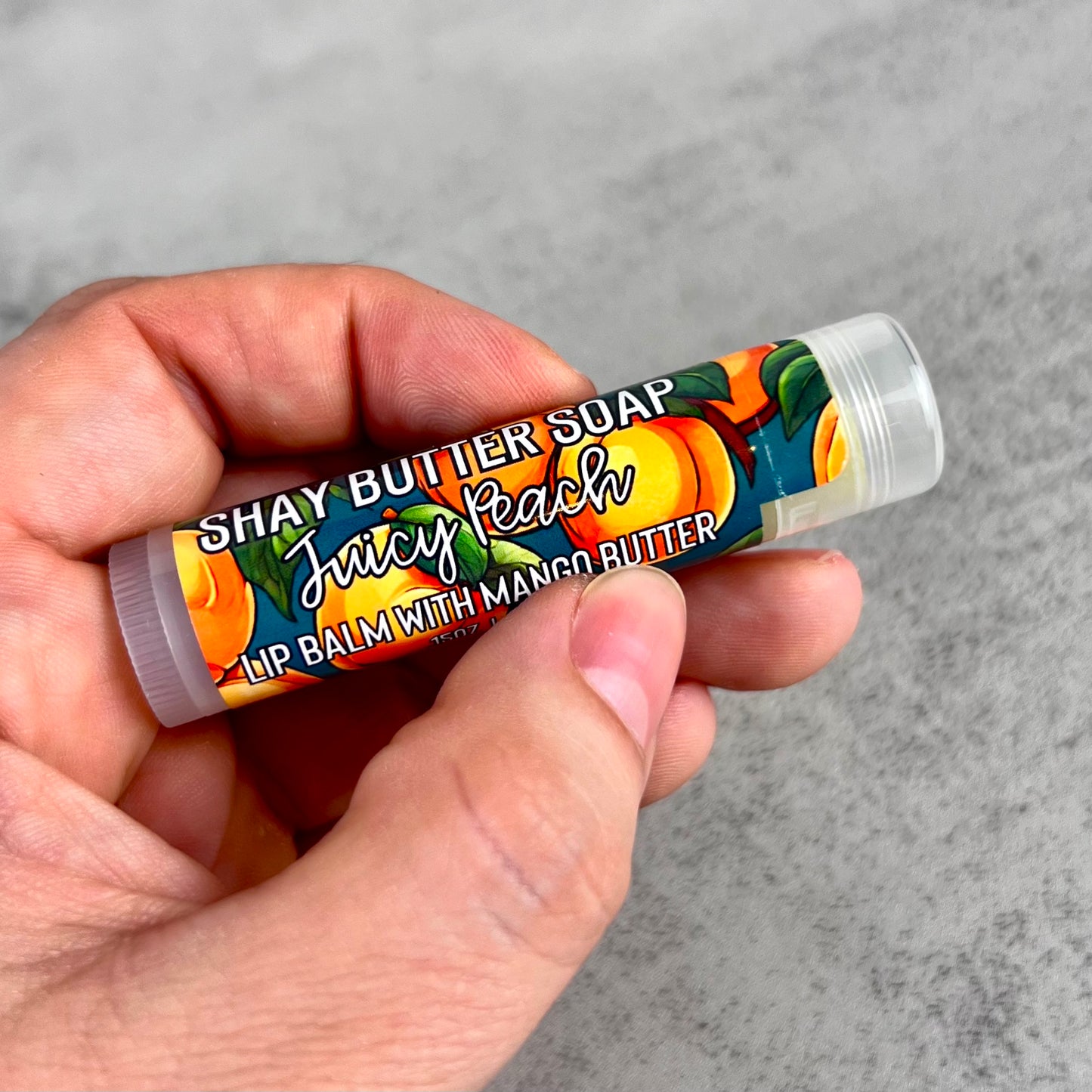 Hand holding a lip balm against a gray background
