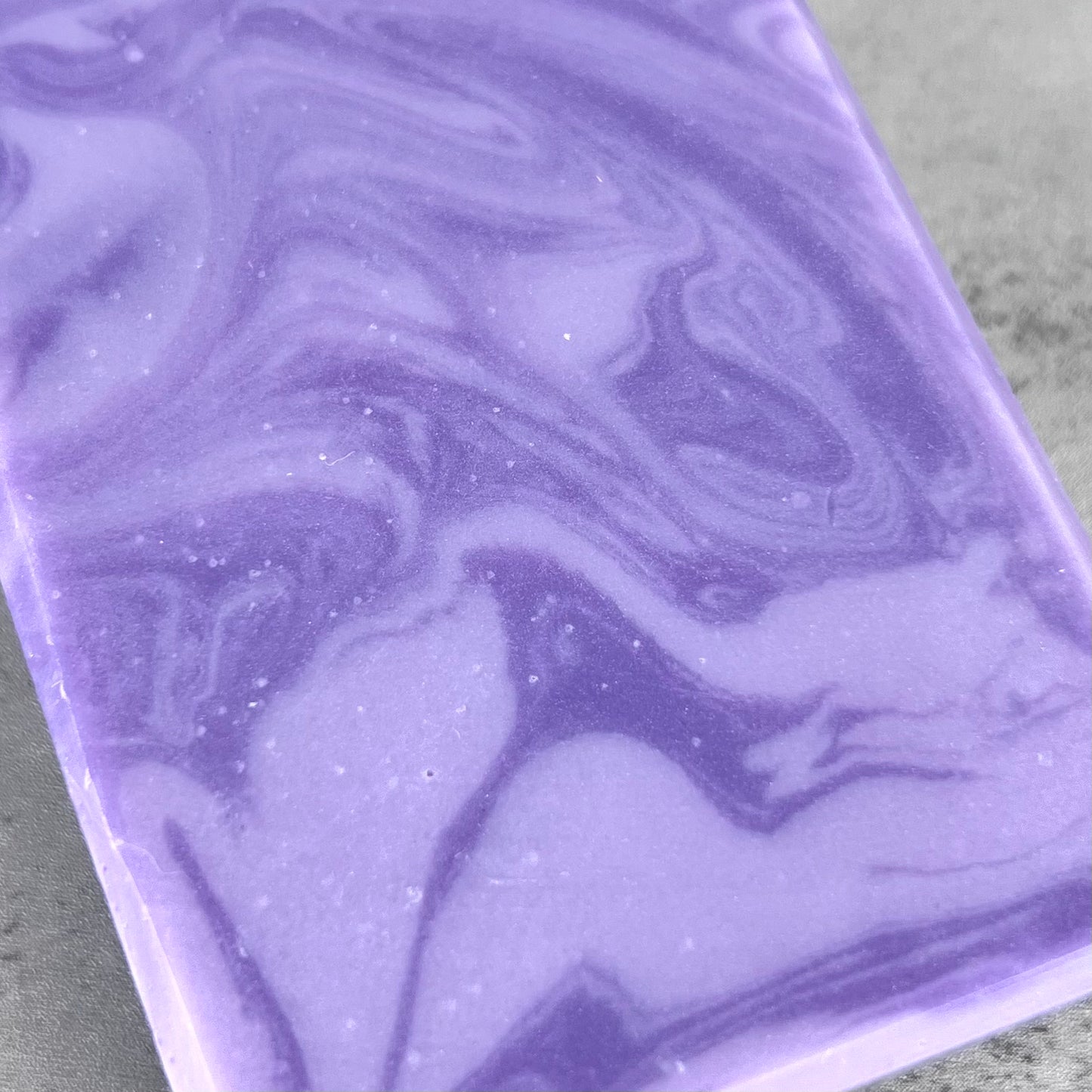 Close-up of a purple marbled soap bar on a gray surface