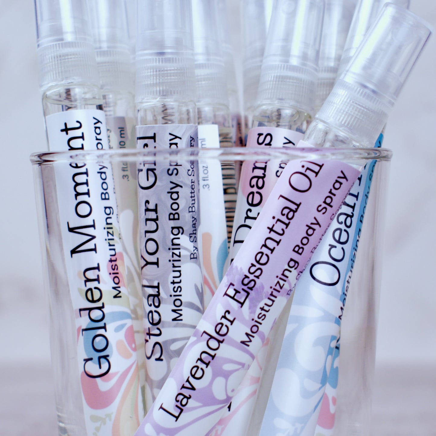 Collection of various body sprays in a glass container.
