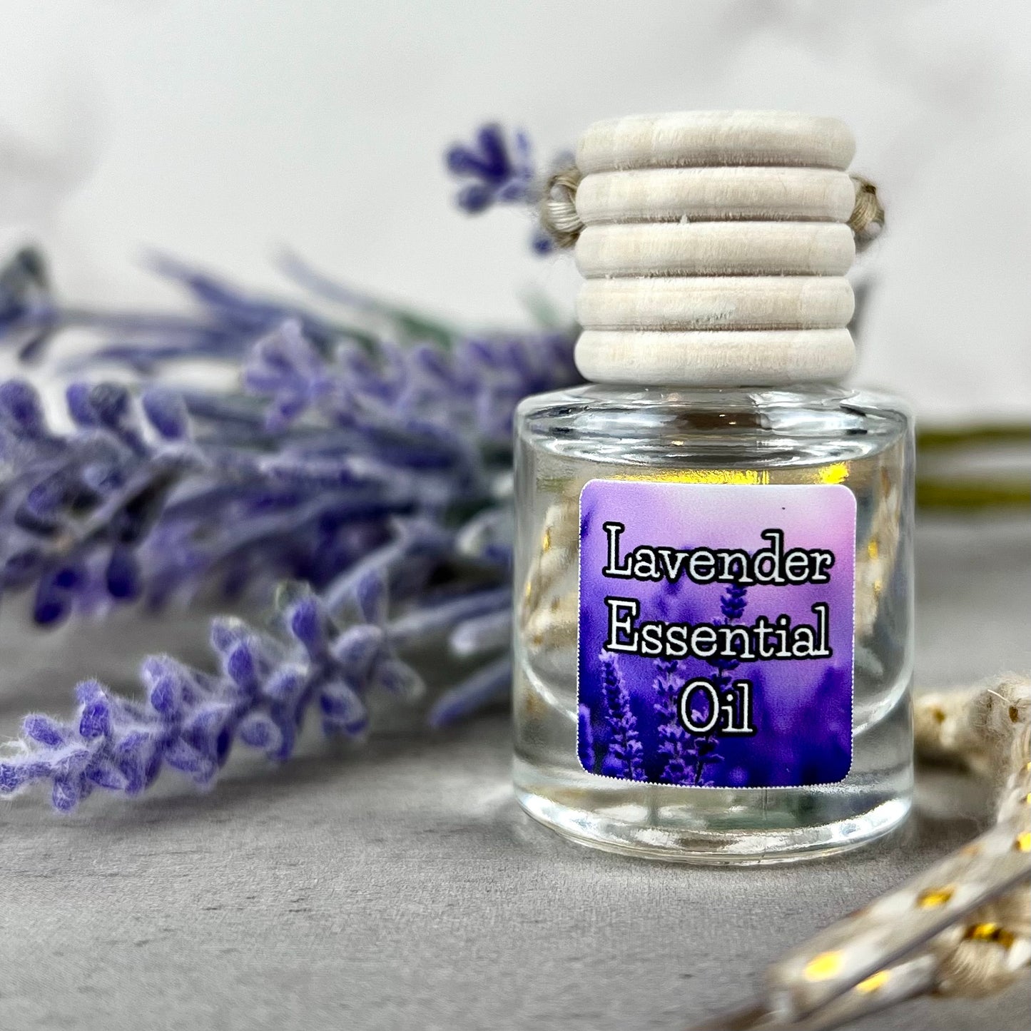 Lavender essential oil car diffuser with purple label in front of lavender plant.
