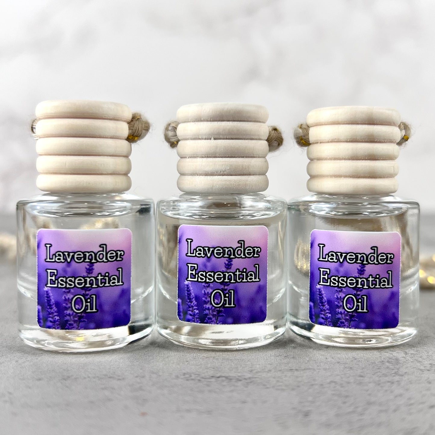Three lavender essential oil car diffusers with purple labels on grey background.