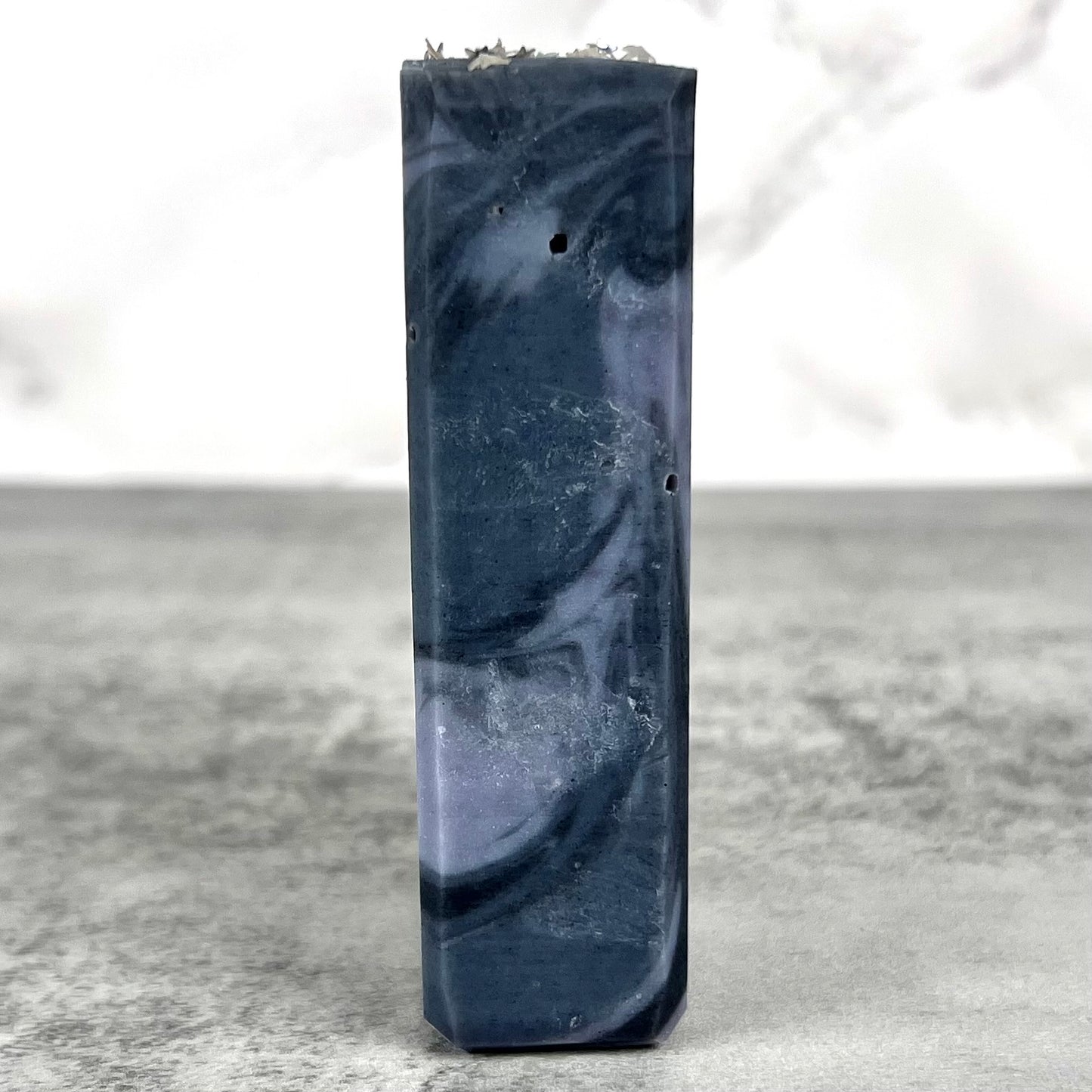 Marbled blue soap bar on a textured surface with a white background
