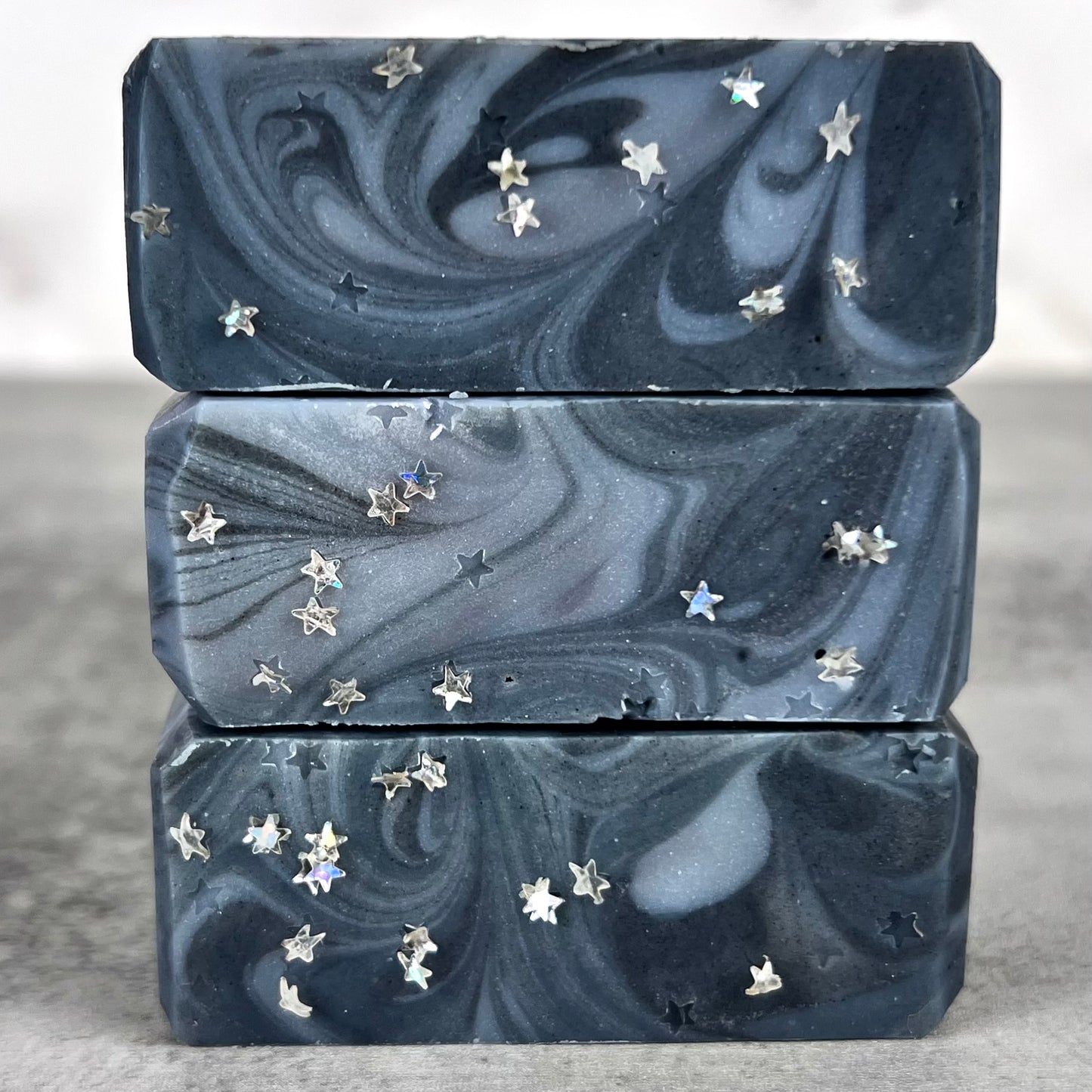 Three marbled soap bars with star-shaped embellishments on a neutral background