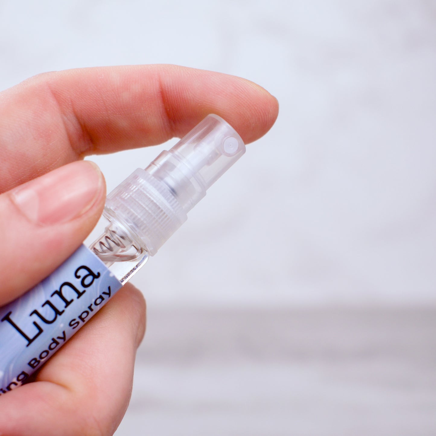 Hand holding a small bottle labeled 'Luna' against a plain background