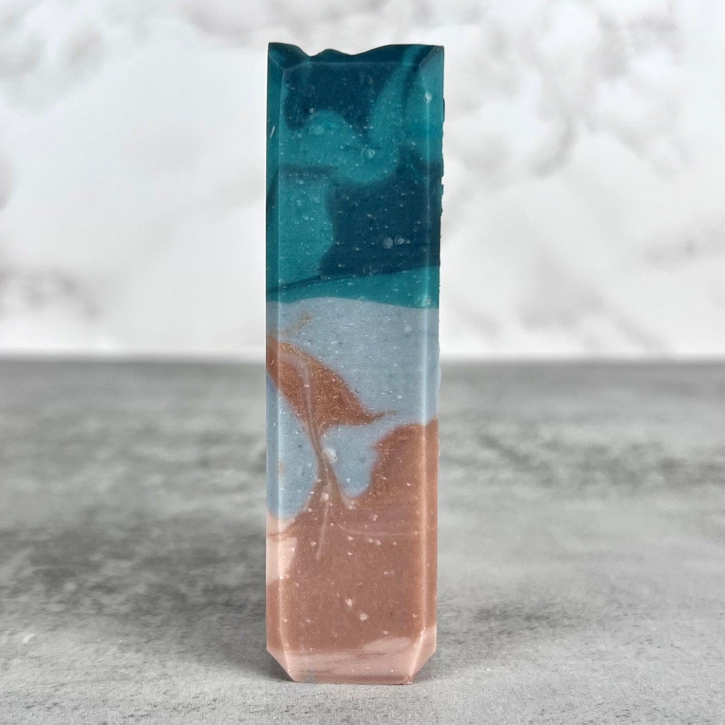 Marbled soap bar with blue and brown colors on a gray surface