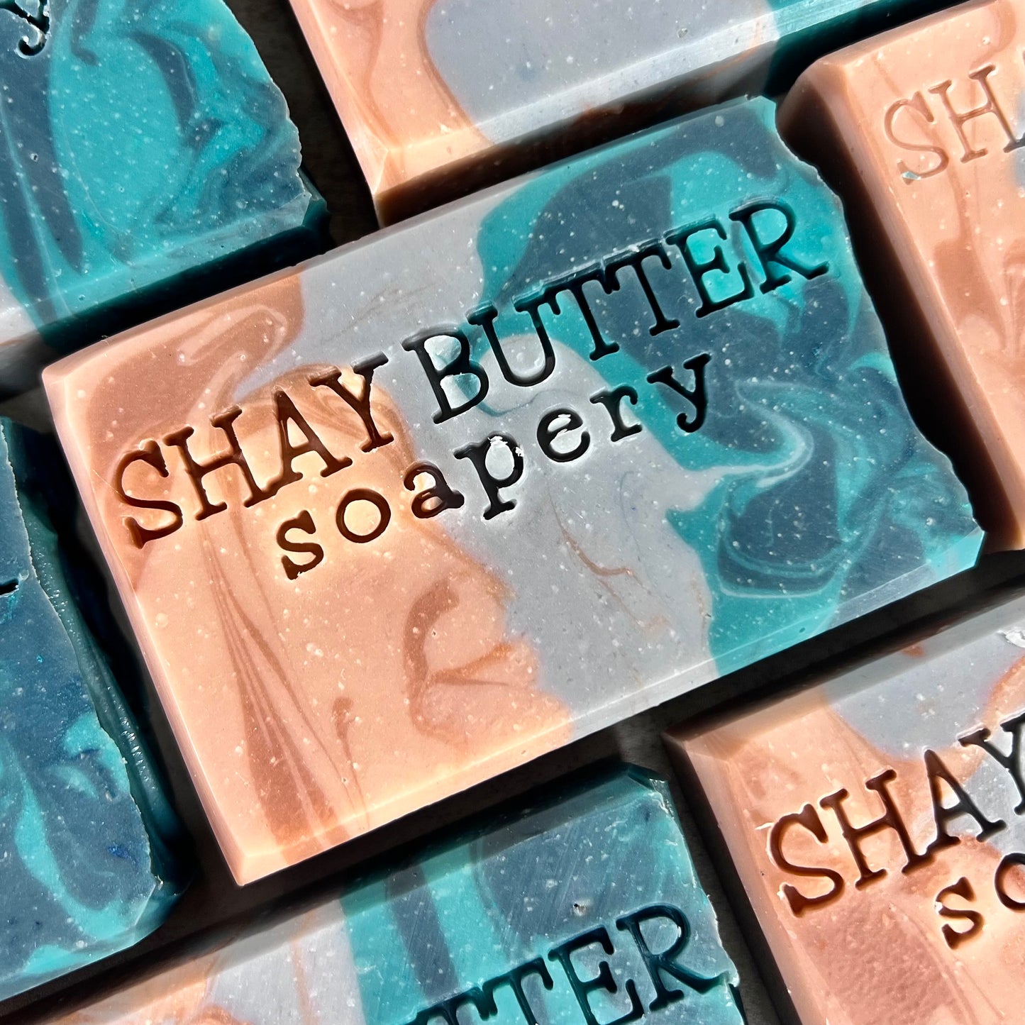 Marbled soap bars with 'SHAY BUTTER soapery' branding.