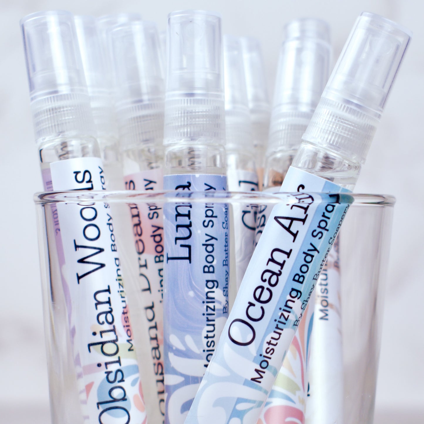 Set of body spray bottles with colorful labels on a white background