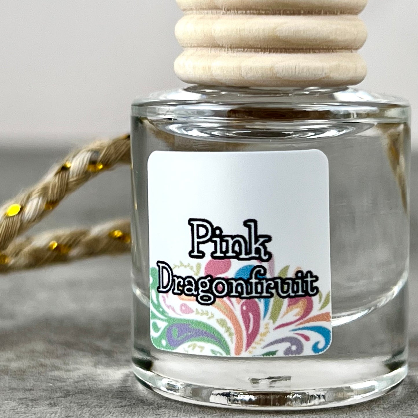 Car diffuser labeled 'Pink Dragonfruit' with a wooden cap on a neutral background