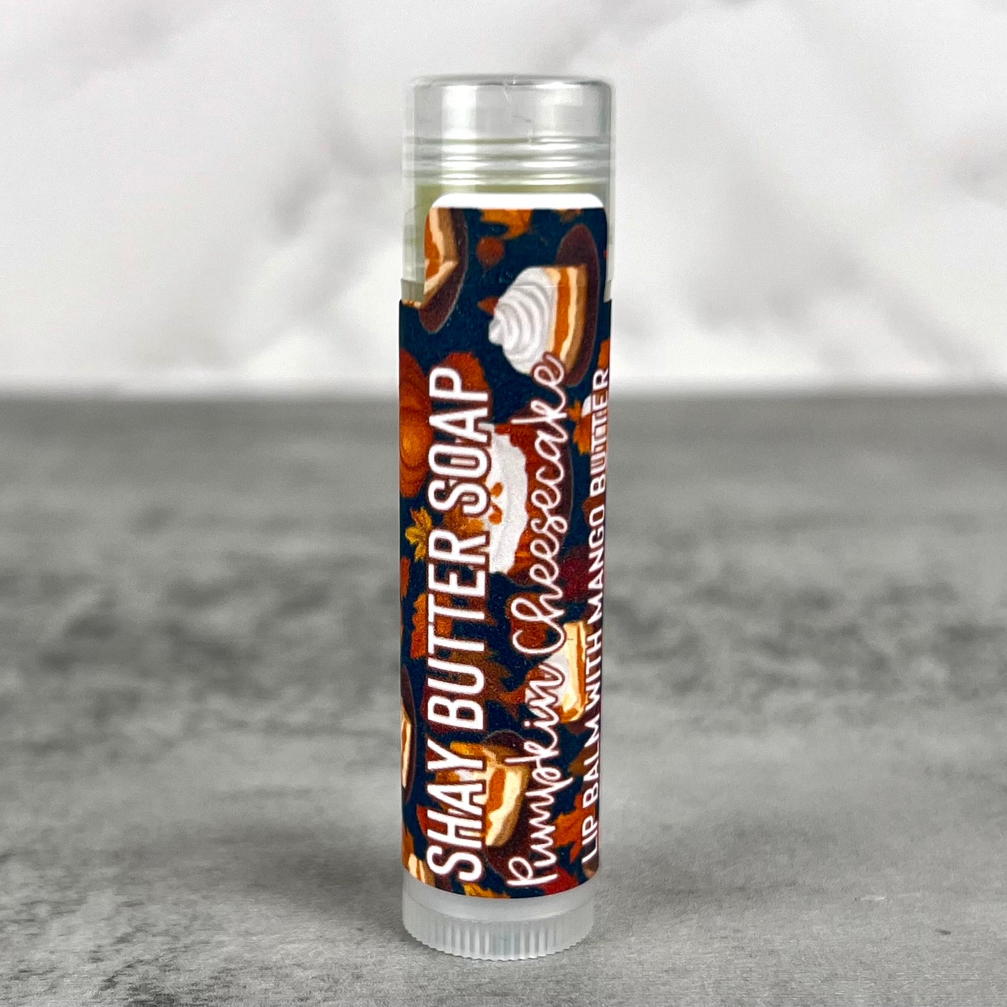 Lip balm tube with pumpkin cheesecake flavor on a gray background