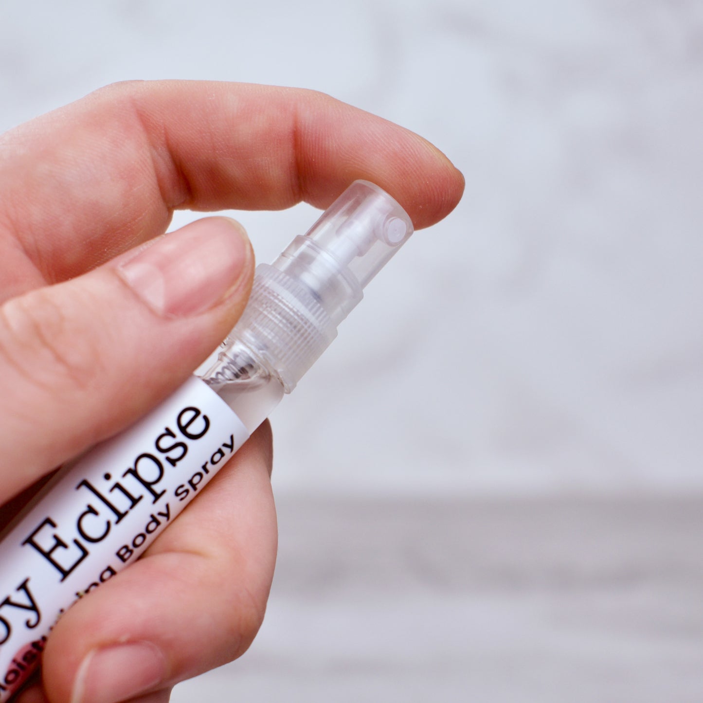 Hand holding a small bottle labeled 'Ruby Eclipse' against a neutral background