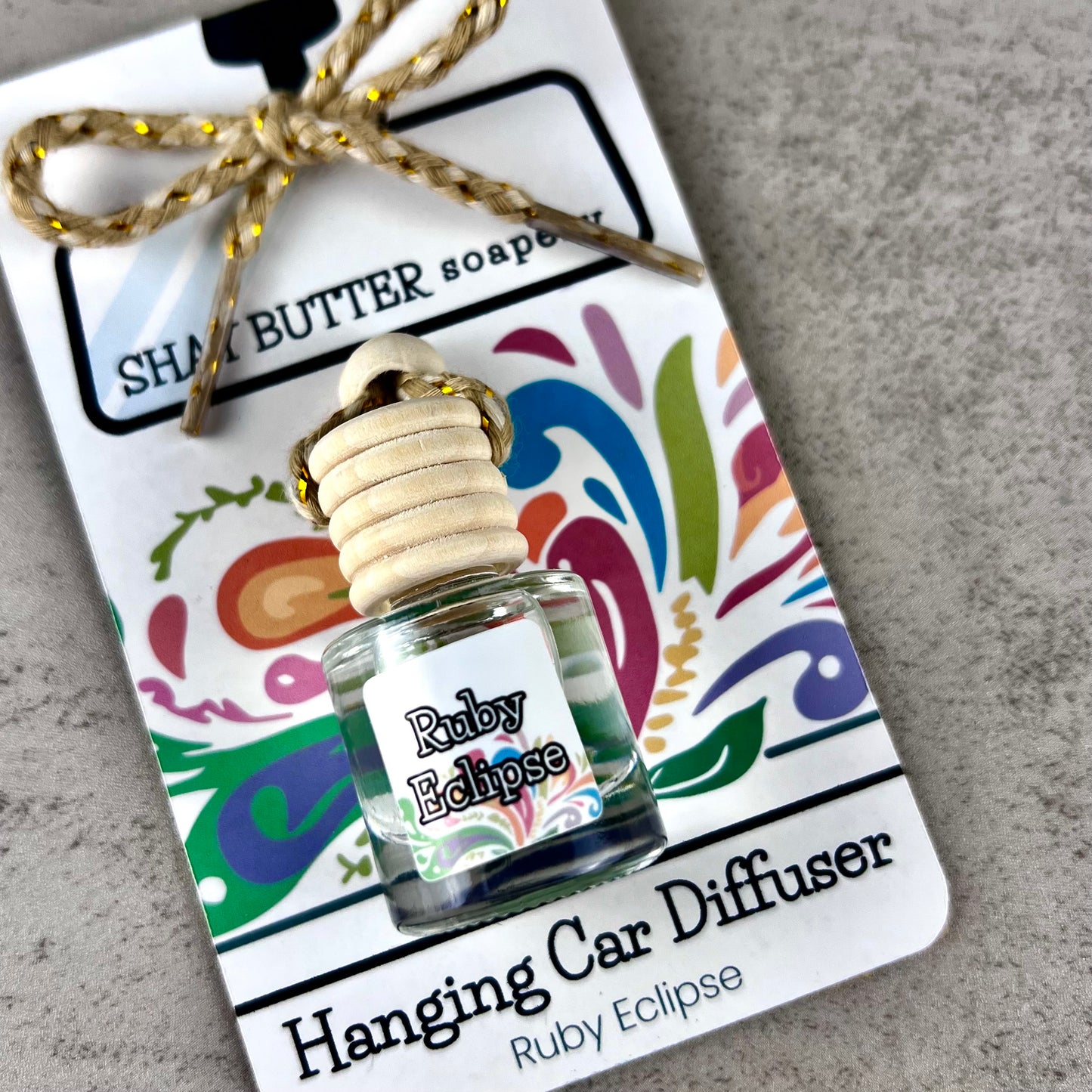 Ruby Eclipse hanging car diffuser on decorative card packaging.