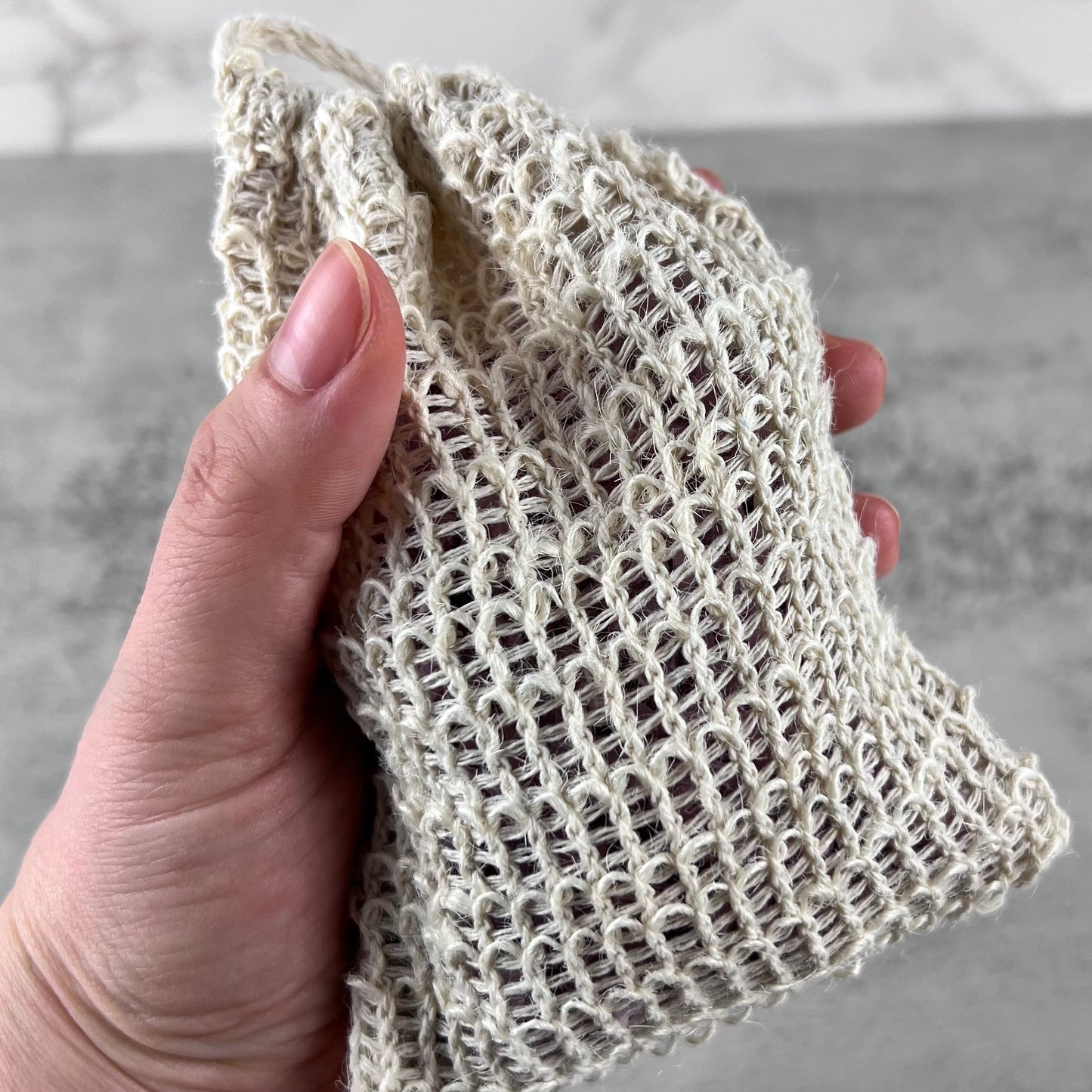 Hand holding a soap scrap bag against a neutral background