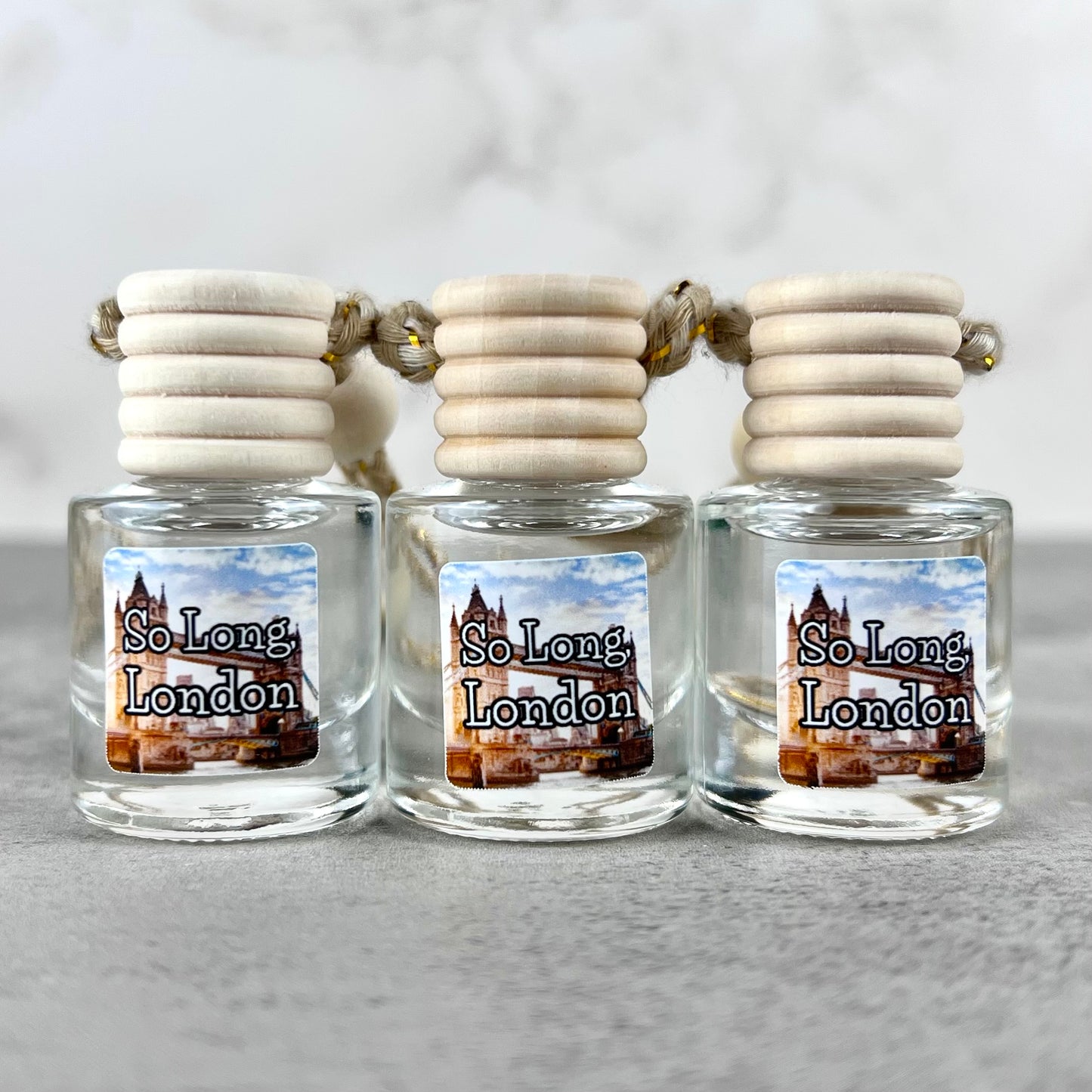 Three hanging car diffusers labeled with "So Long, London" on a grey background.