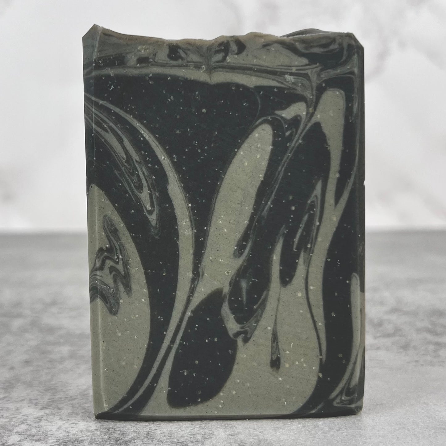 Bar of soap with black and gray marbled design on a gray background