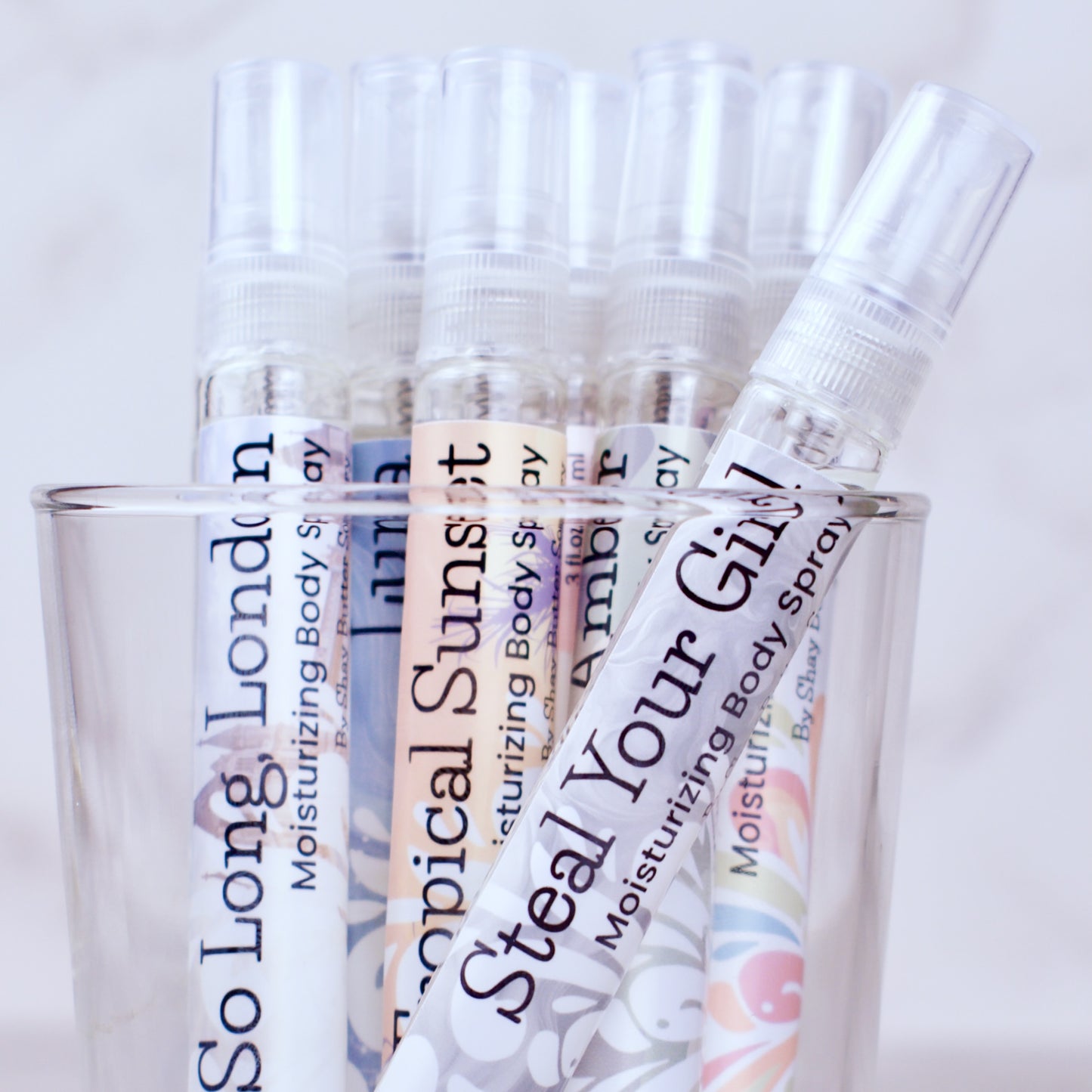 Body spray bottles with colorful labels on a light background