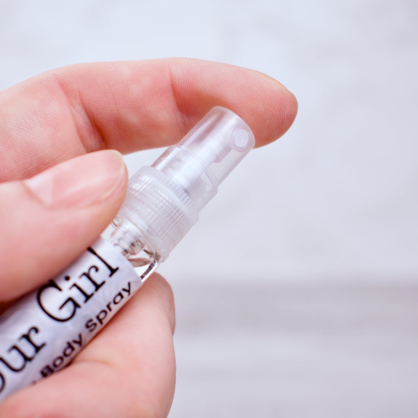 Hand holding a small spray bottle labeled 'Steal Your Girl' against a light background