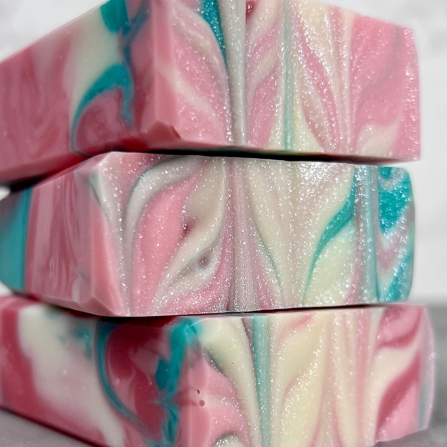 Colorful marbled soap bars with pink, blue, and white swirls on a white background