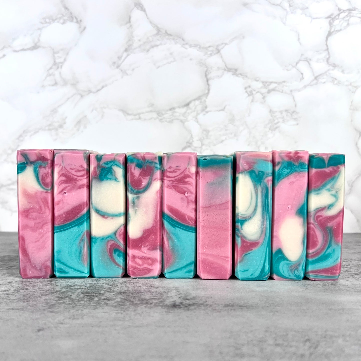 Marbled soap bars in pink, blue, and white on a marble background