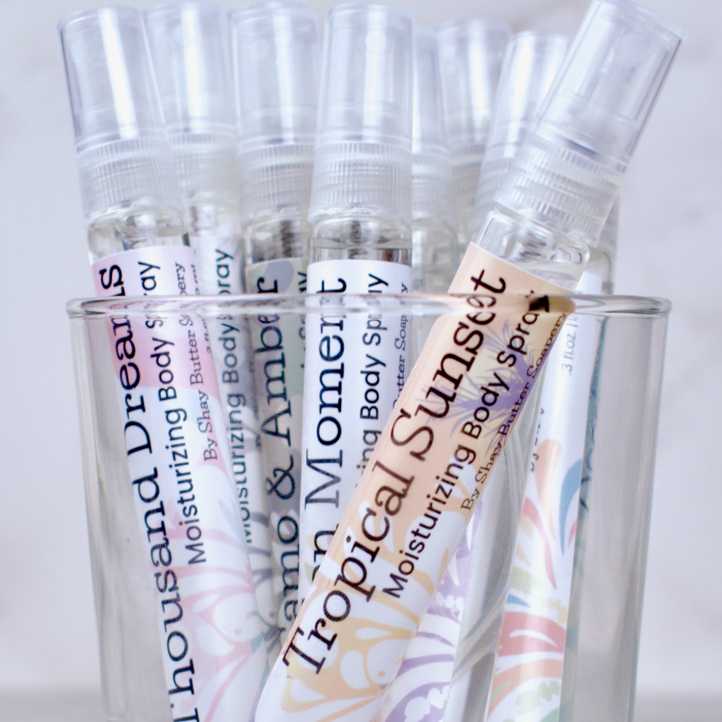 Collection of moisturizing body spray bottles with visible labels on a white background