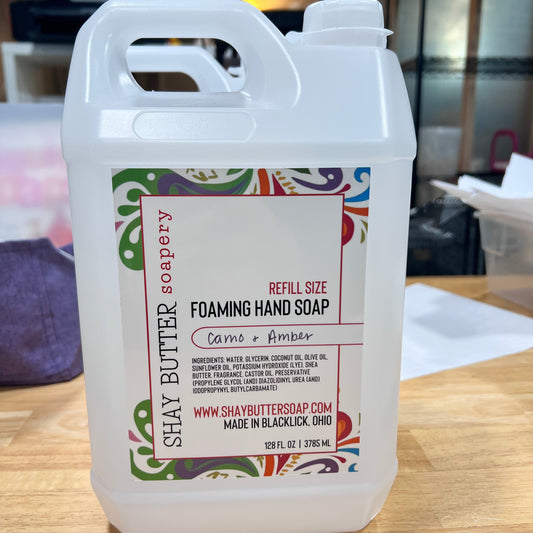 Large container of foaming hand soap with colorful label on a wooden surface