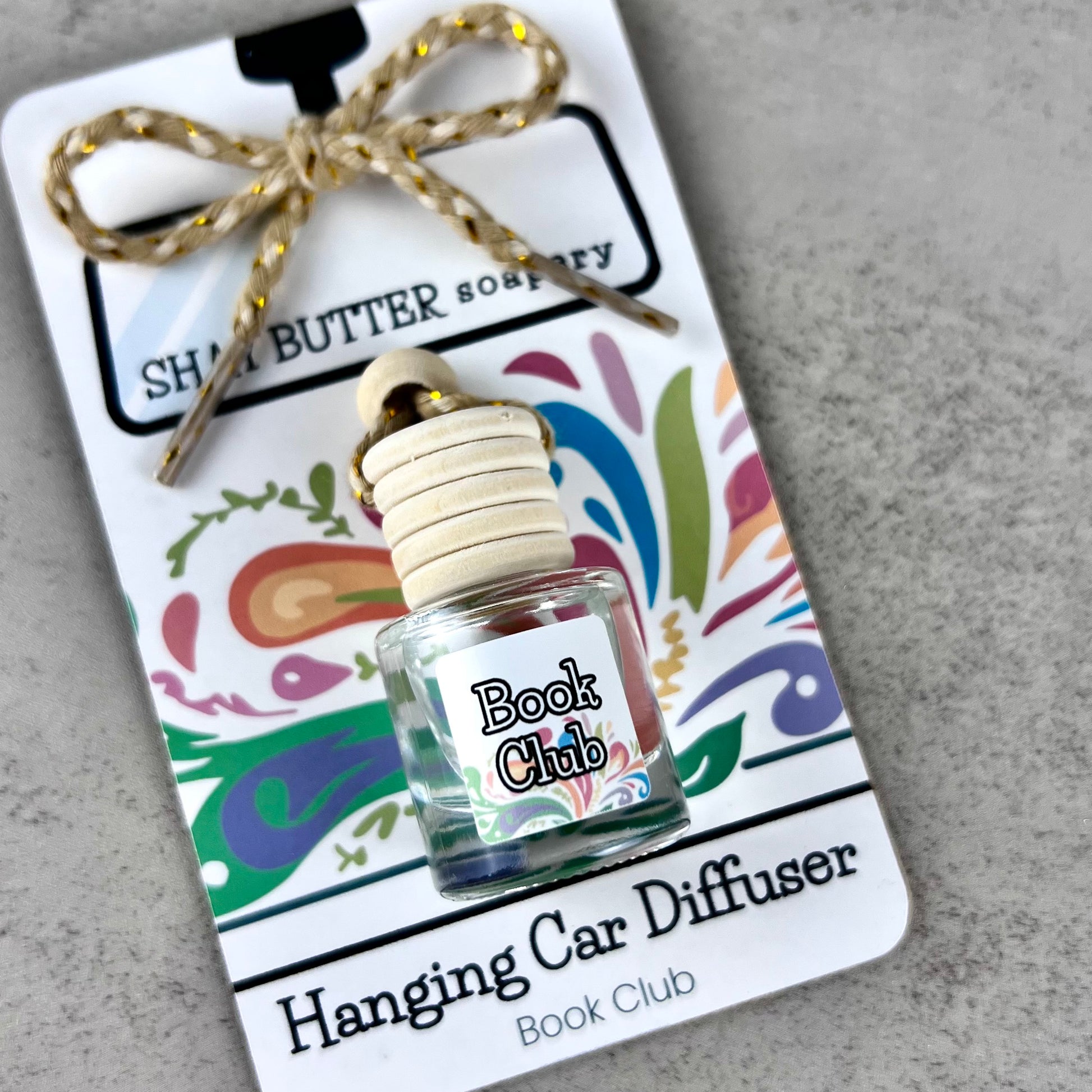 Hanging car diffuser with 'Book Club' label on a decorative packaging card.