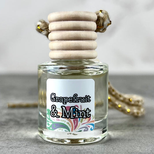 Hanging car diffuser labeled 'Grapefruit & Mint' on a neutral background
