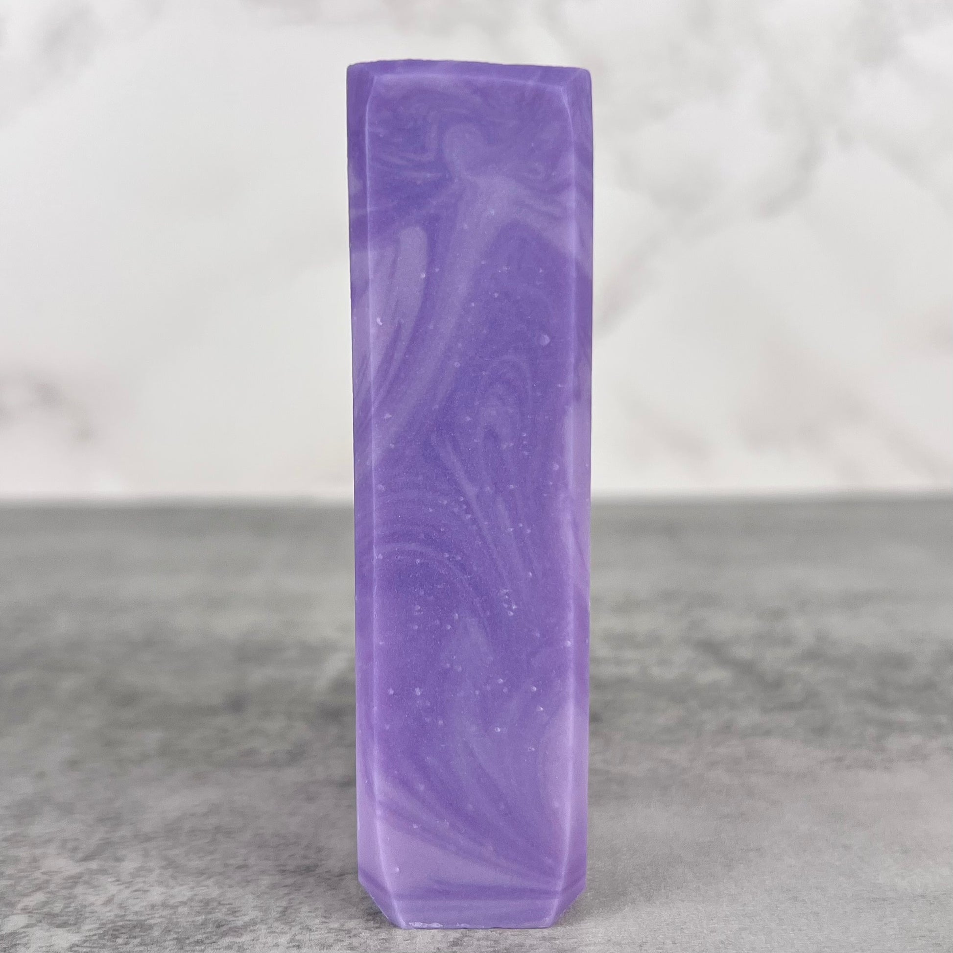Purple marbled soap bar on a gray surface with a light gray background