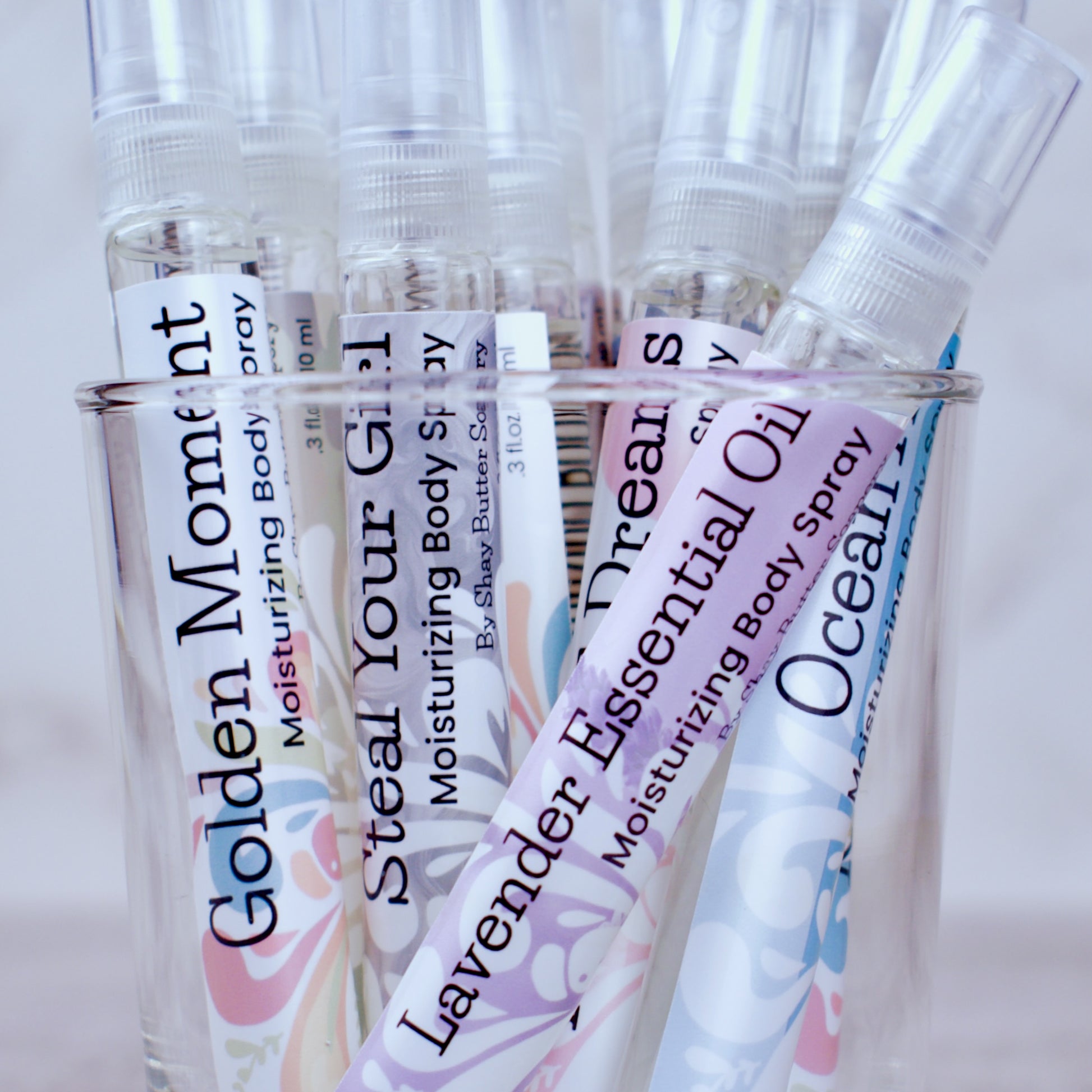 Collection of various body sprays  in a glass container.