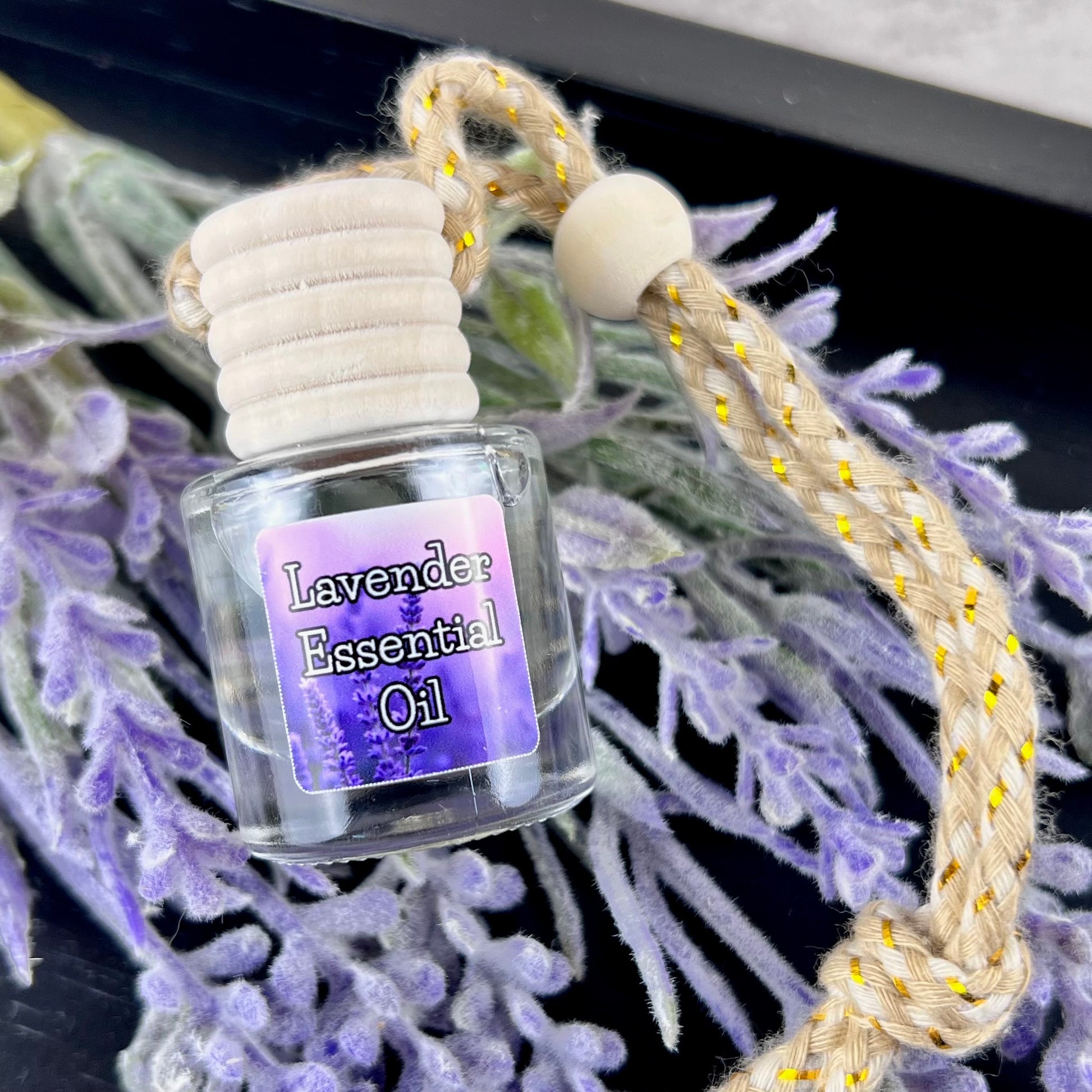 Lavender essential oil car diffuser with purple label on a bed of lavender flowers.