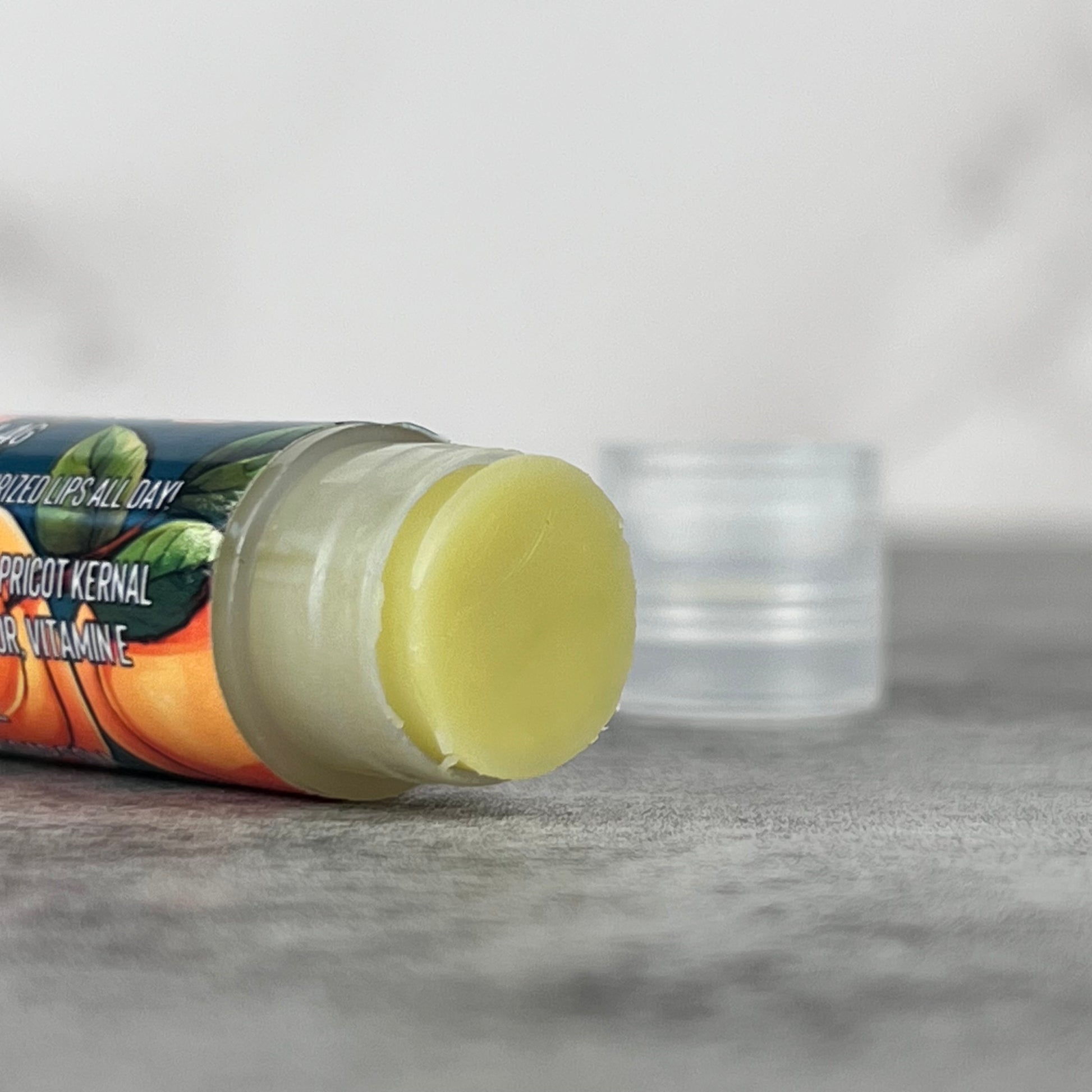 Lip balm without cap on grey surface.