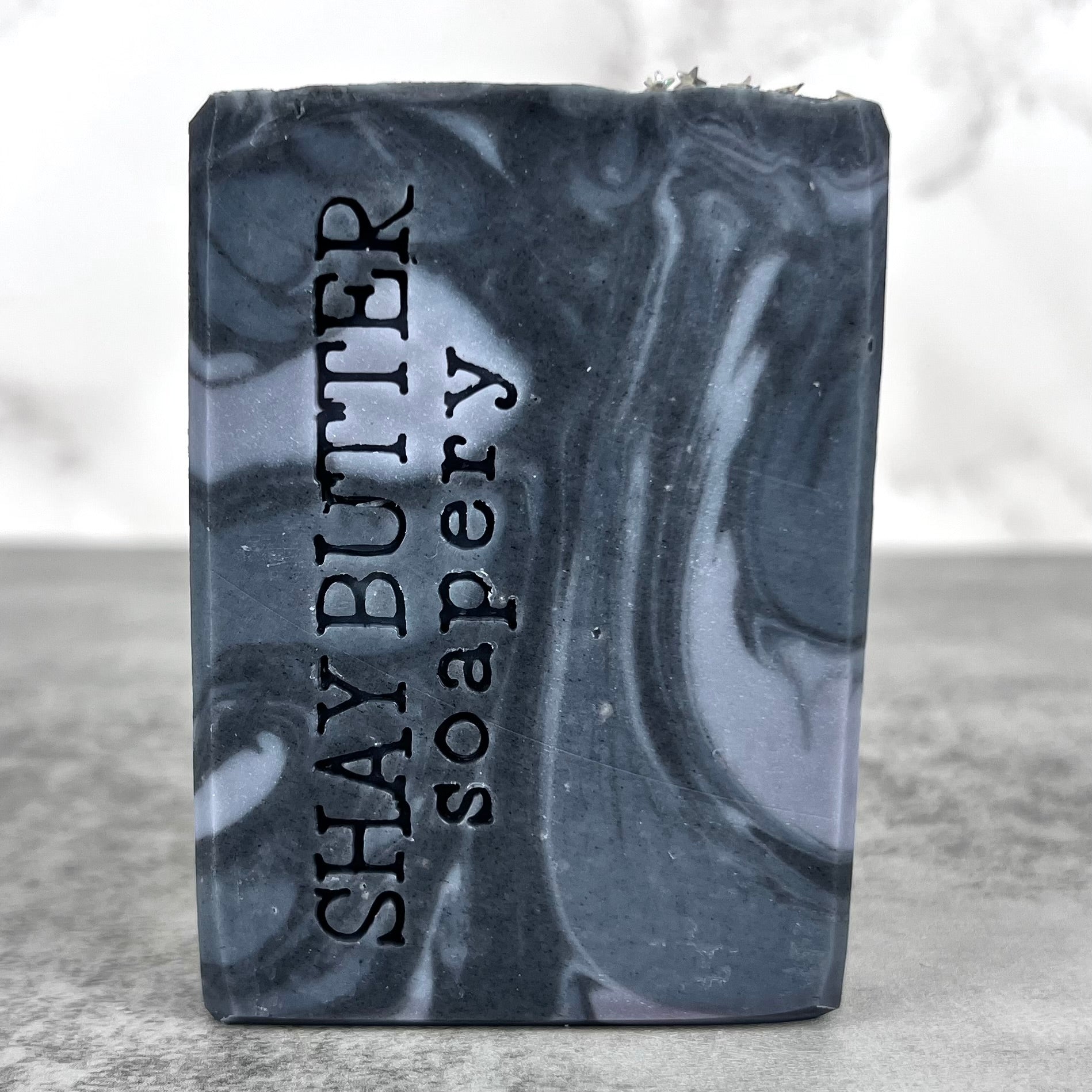Bar of soap with 'Shay Butter Soapery' branding on a gray surface.