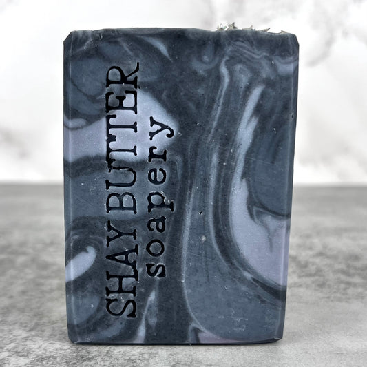 Bar of soap with 'Shay Butter Soapery' branding on a gray surface.