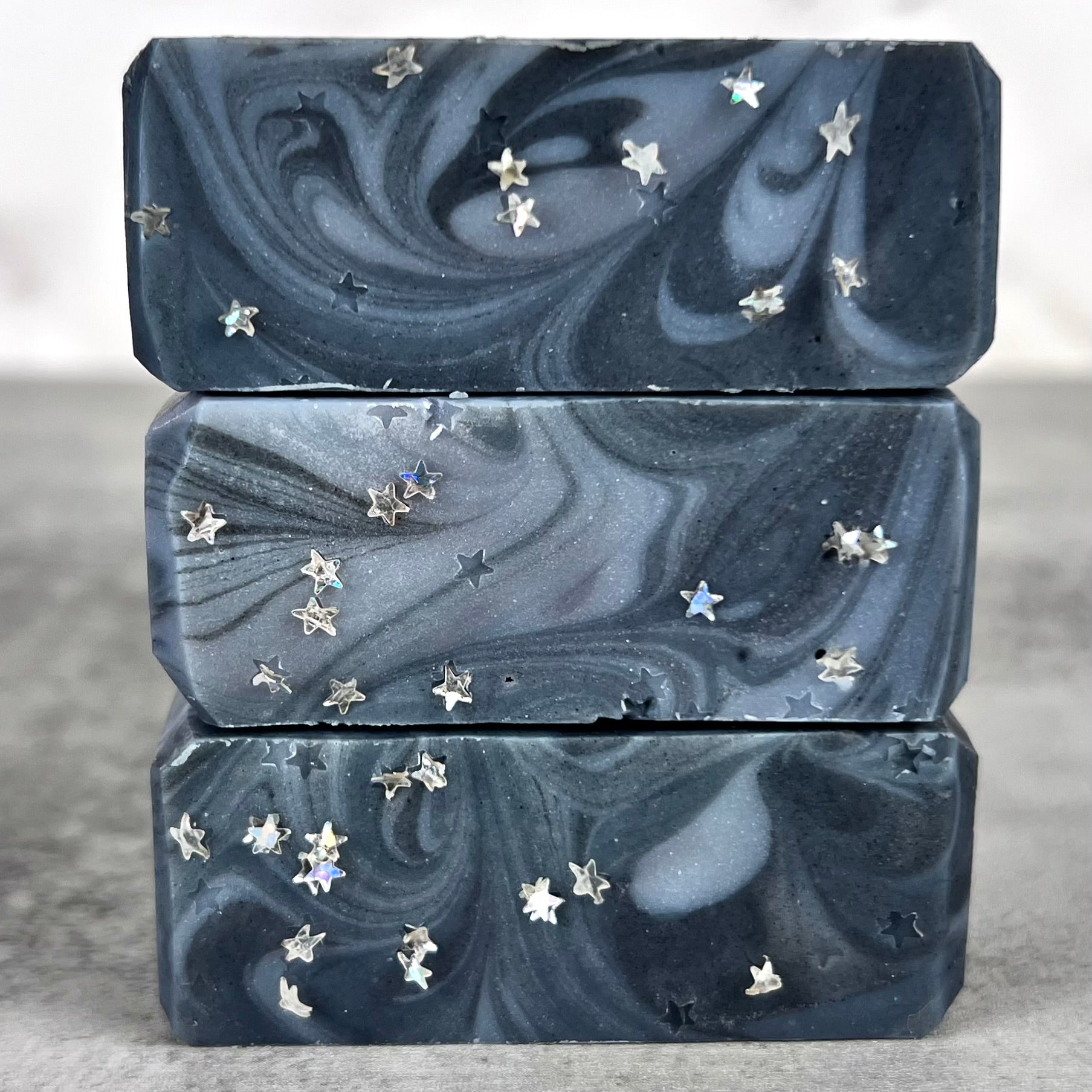 Three marbled soap bars with star-shaped embellishments on a neutral background