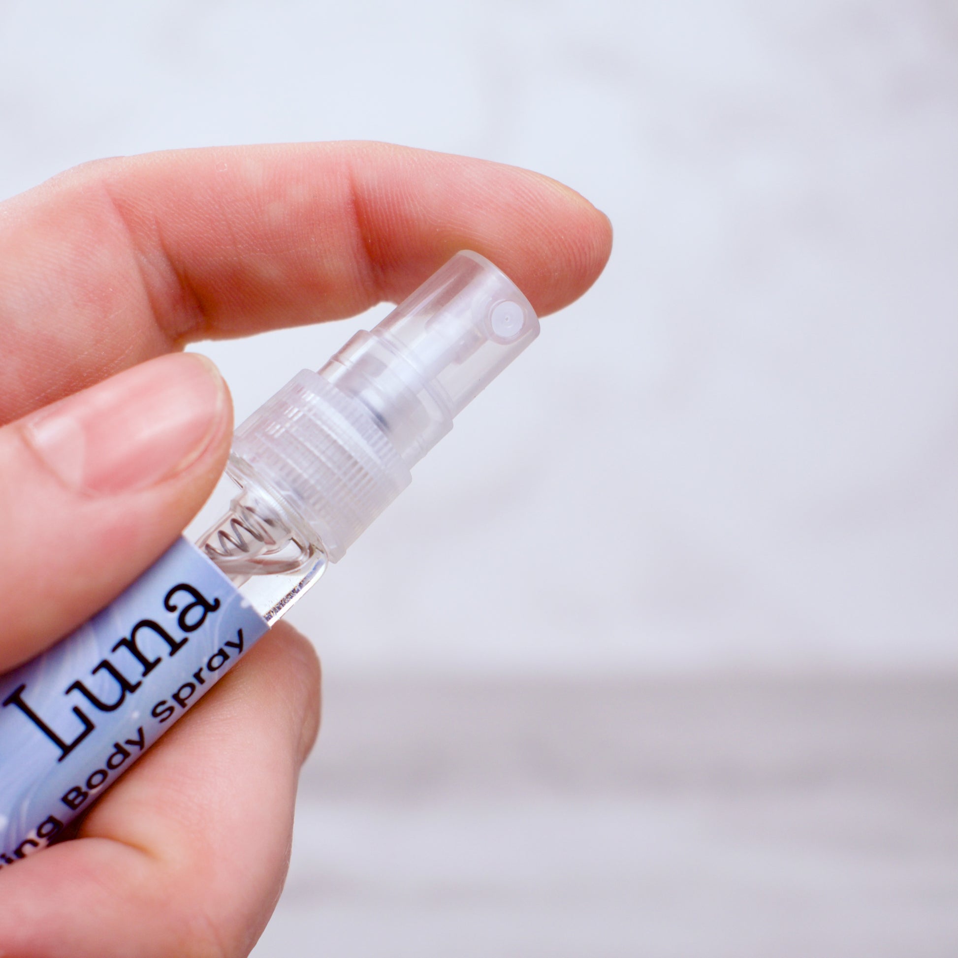 Hand holding a small bottle labeled 'Luna' against a plain background