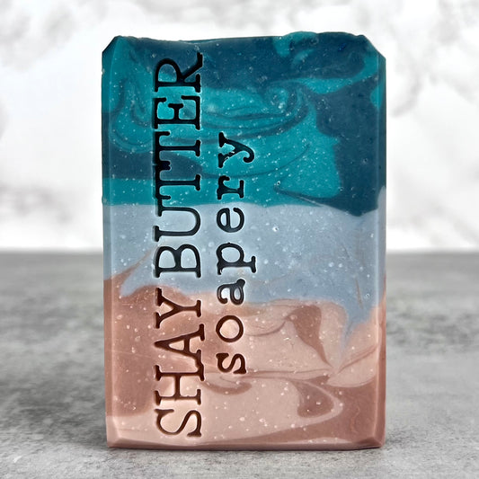 Bar of soap with 'Shay Butter Soapery' branding on a gray surface.
