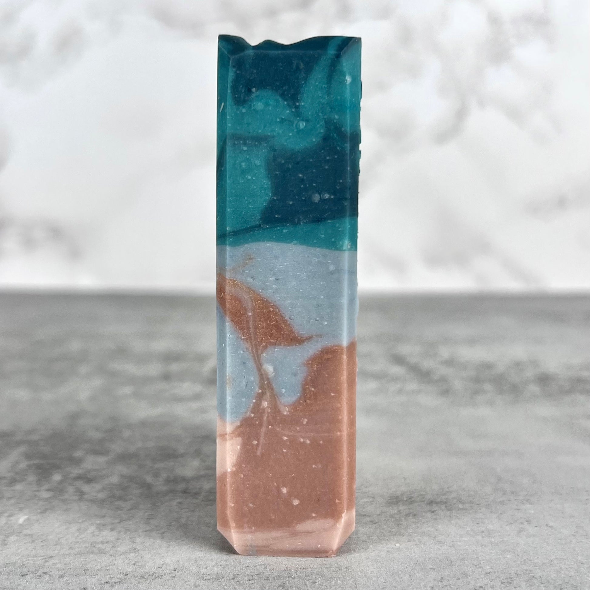 Marbled soap bar with blue and brown colors on a gray surface