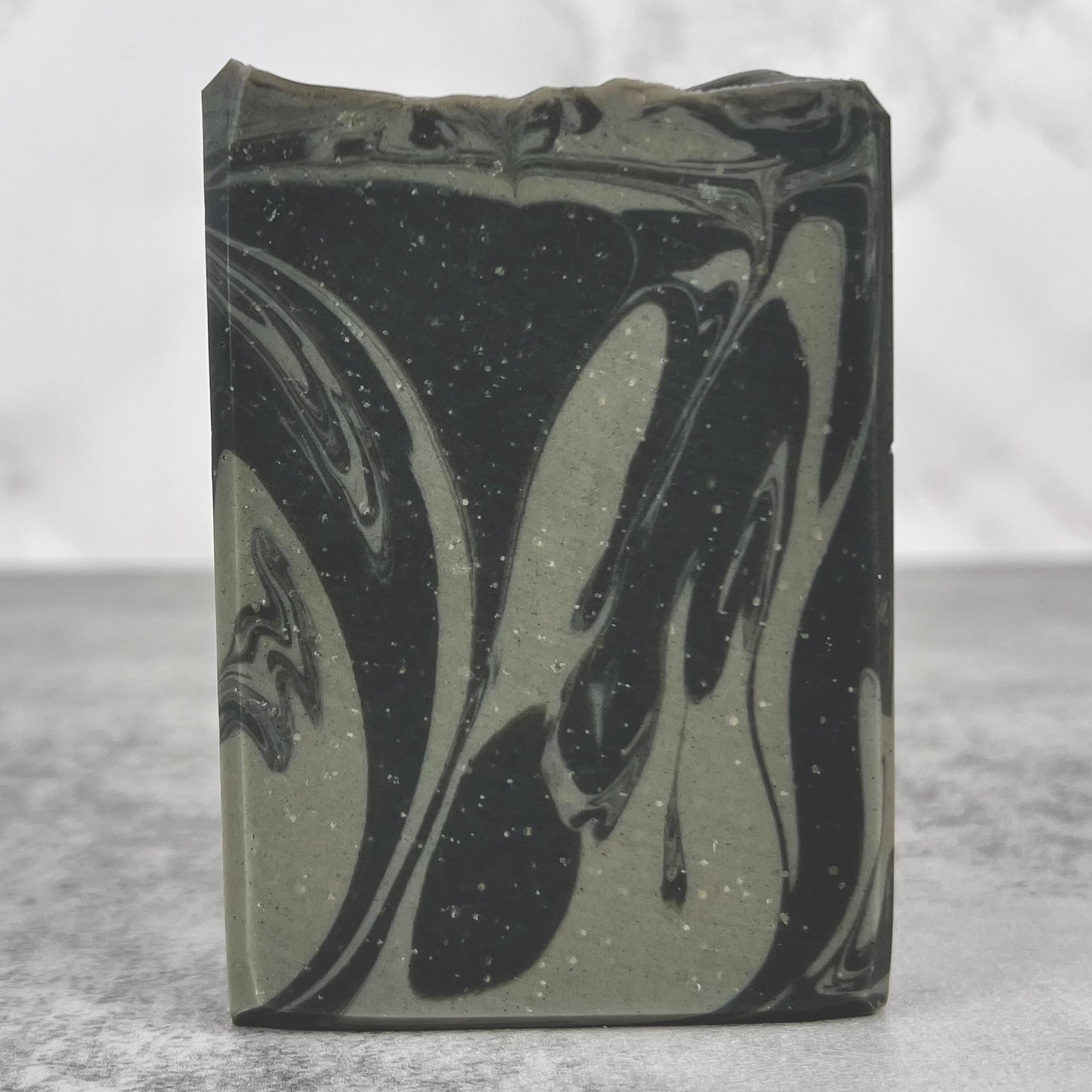Bar of soap with black and gray marbled design on a gray background