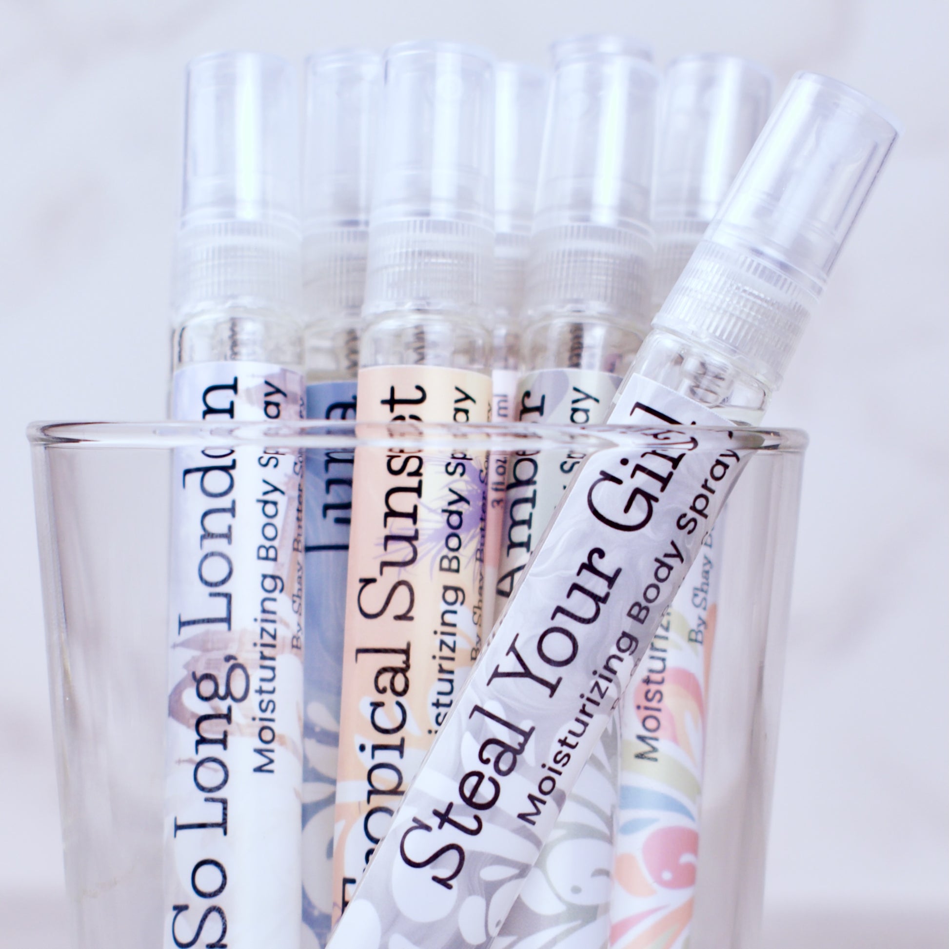 Body spray bottles with colorful labels on a light background