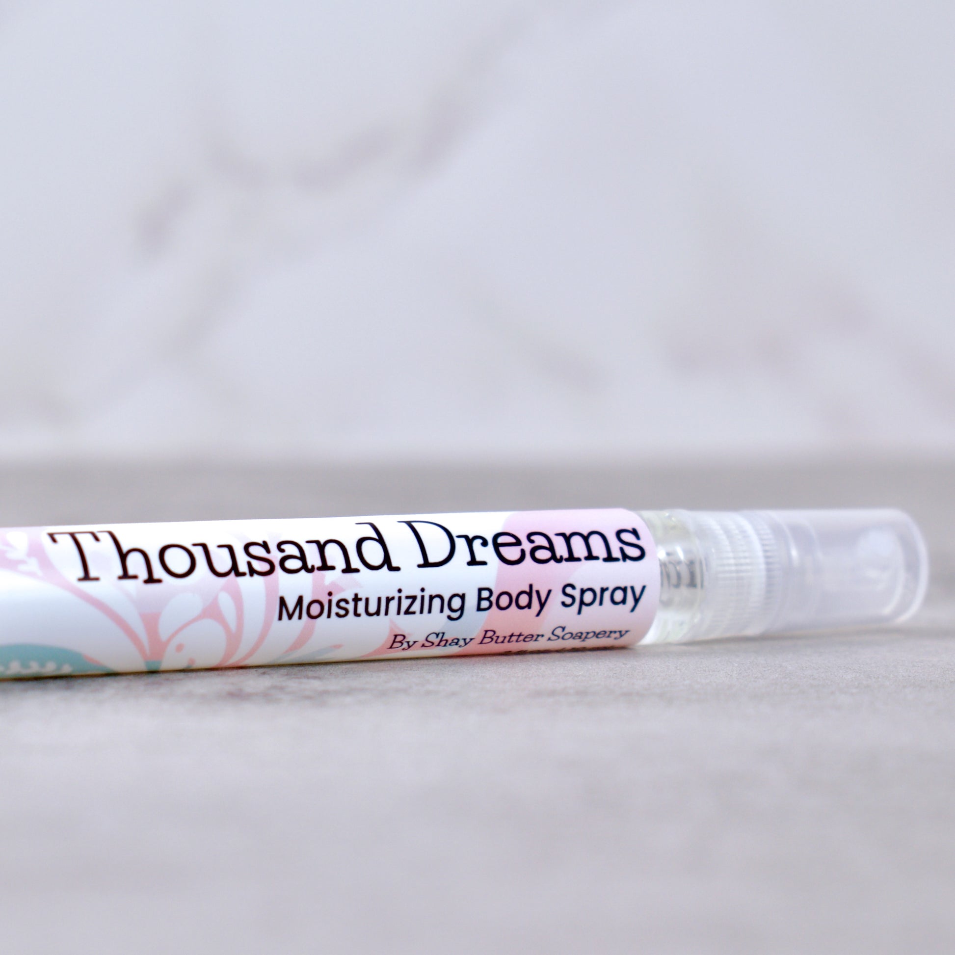 Moisturizing body spray labeled 'Thousand Dreams' on a light gray background