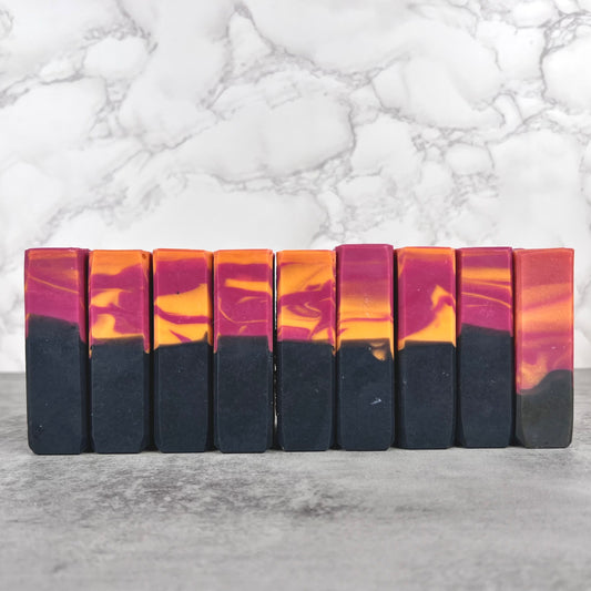 Row of marbled soap bars with black, orange, and purple colors on a marble background